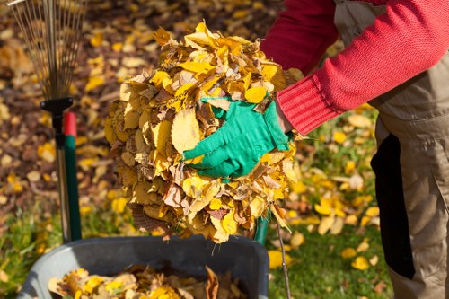 Operative wearing PPE while clearing garden waste for insured garden clearance company